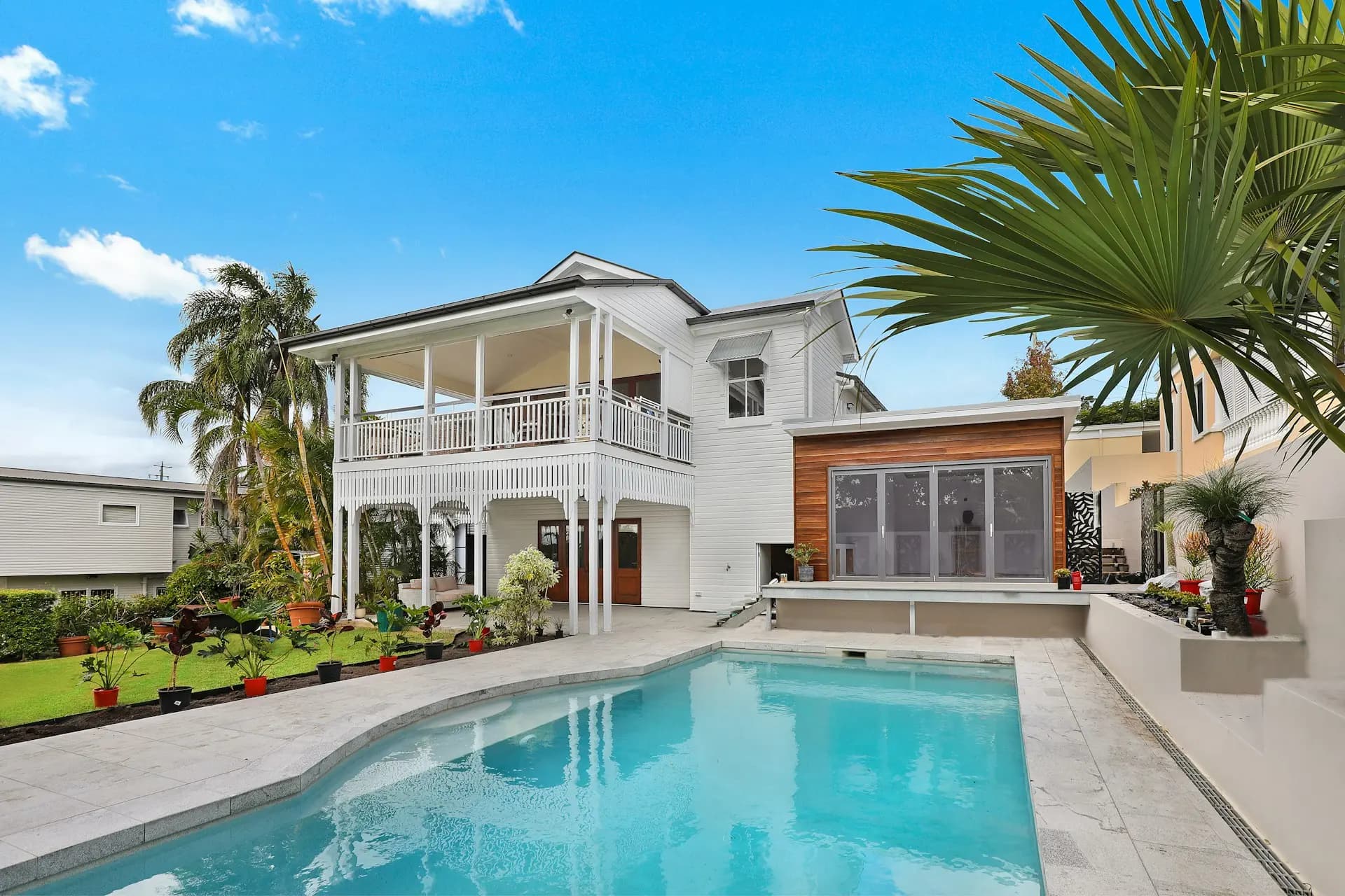 White home with a wraparound veranda beside a pool